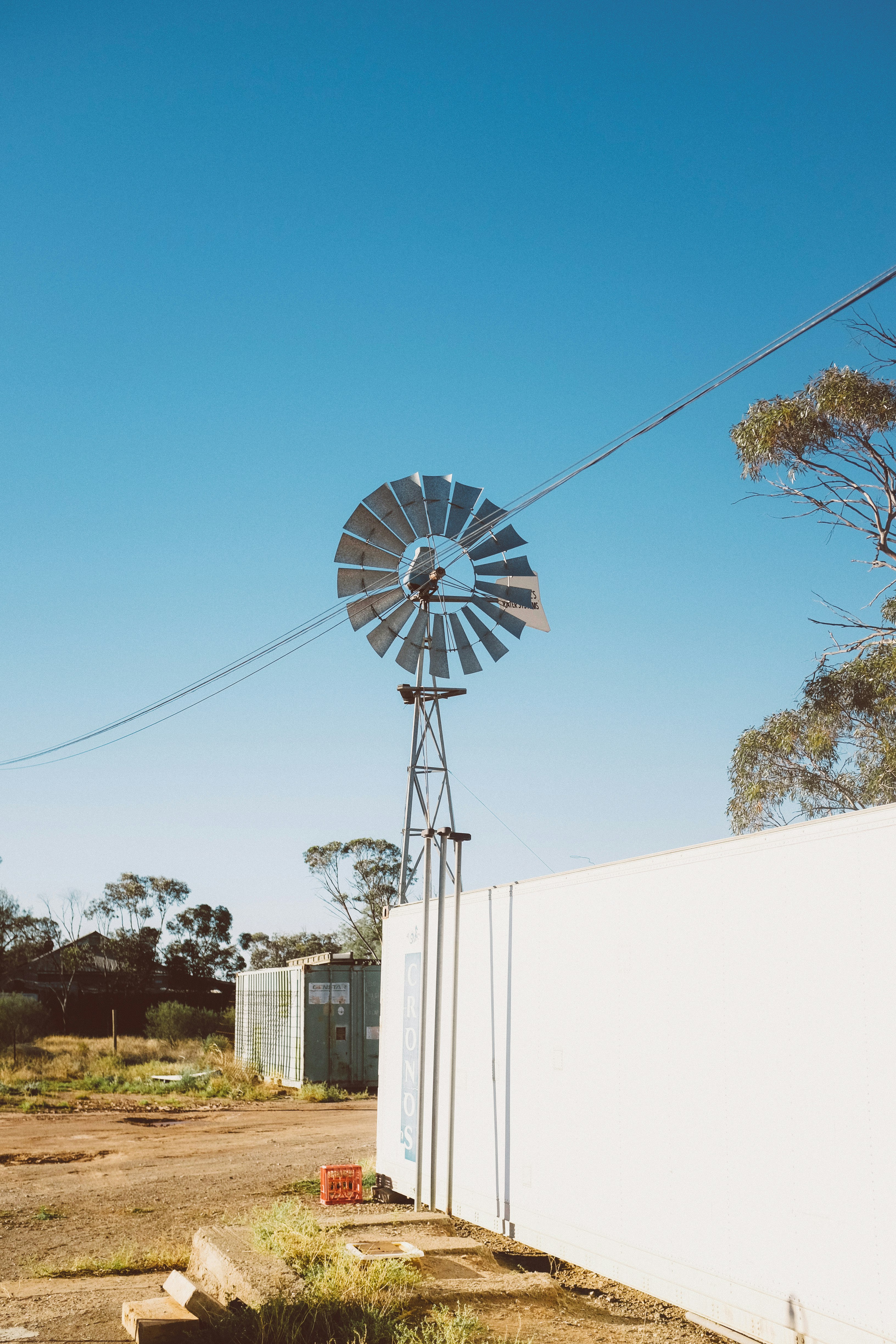 white and gray wind mill near white building during daytime